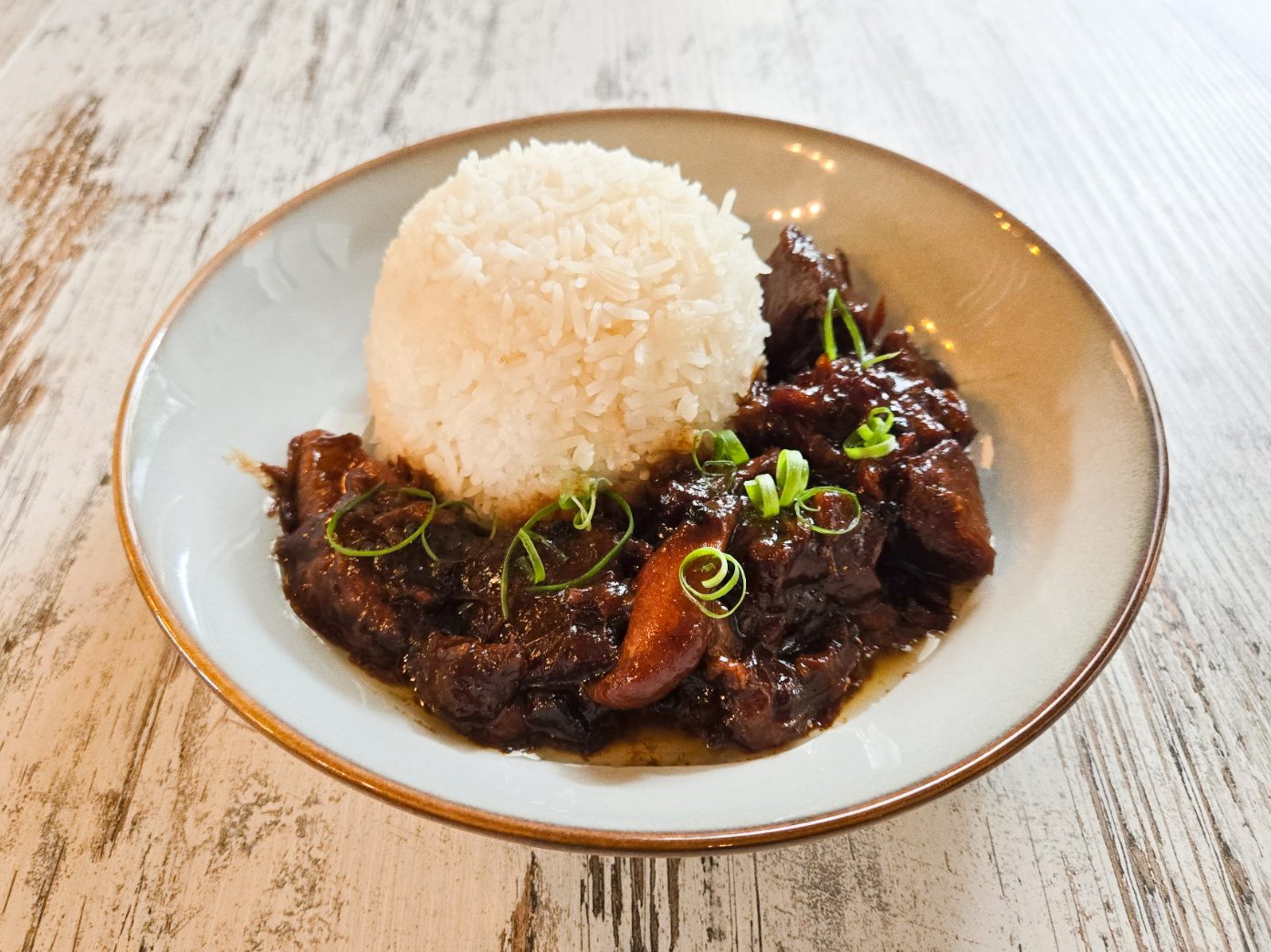 Filipino chicken and pork adobo rice bowl — tender marinated meat simmered in soy sauce, vinegar, garlic, and spices, served over steamed white rice.