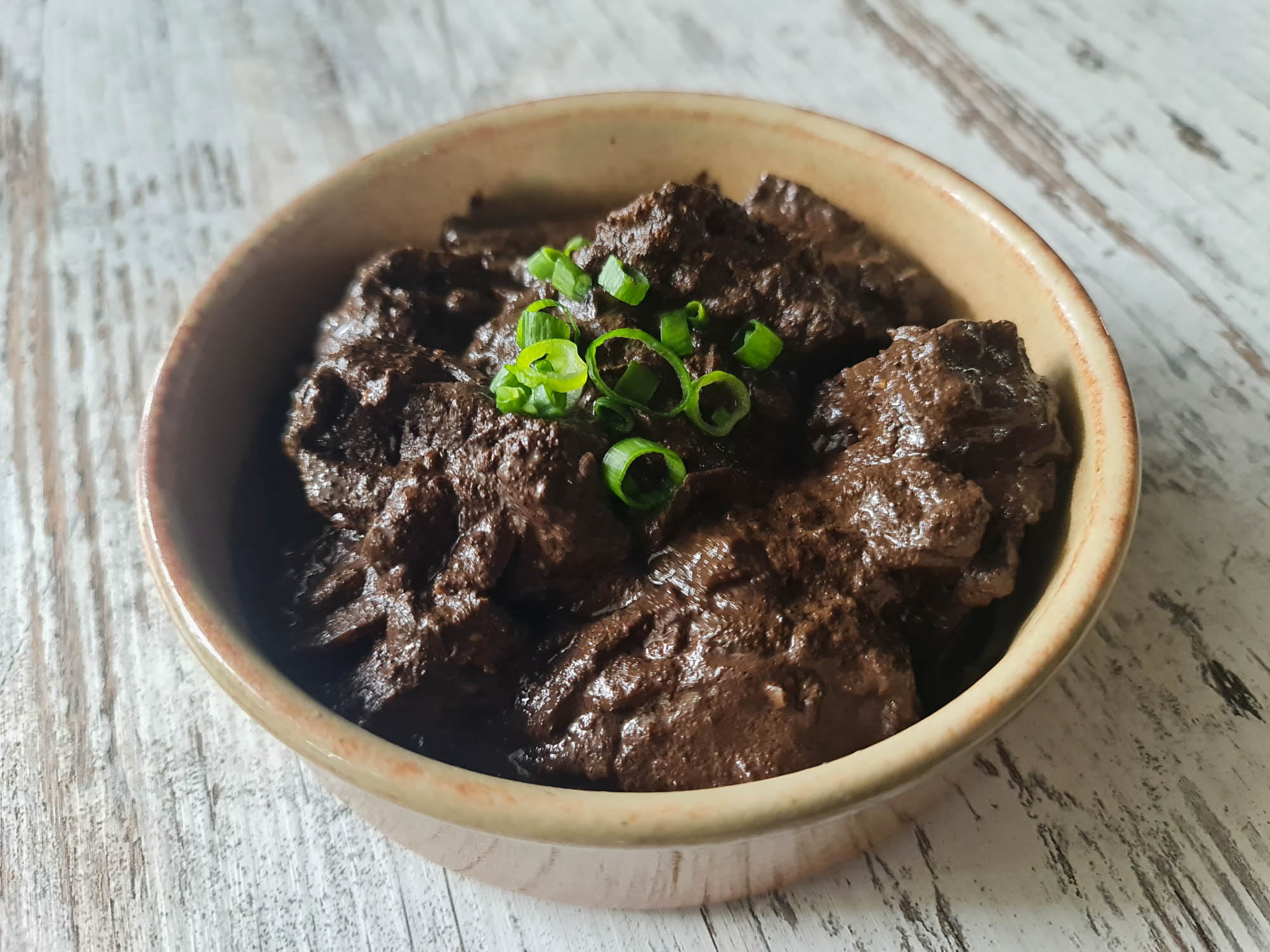 Crispy pork belly in rich Filipino dinuguan sauce with chili, vinegar, and lemongrass at Descanso Café in Newtown Sydney.