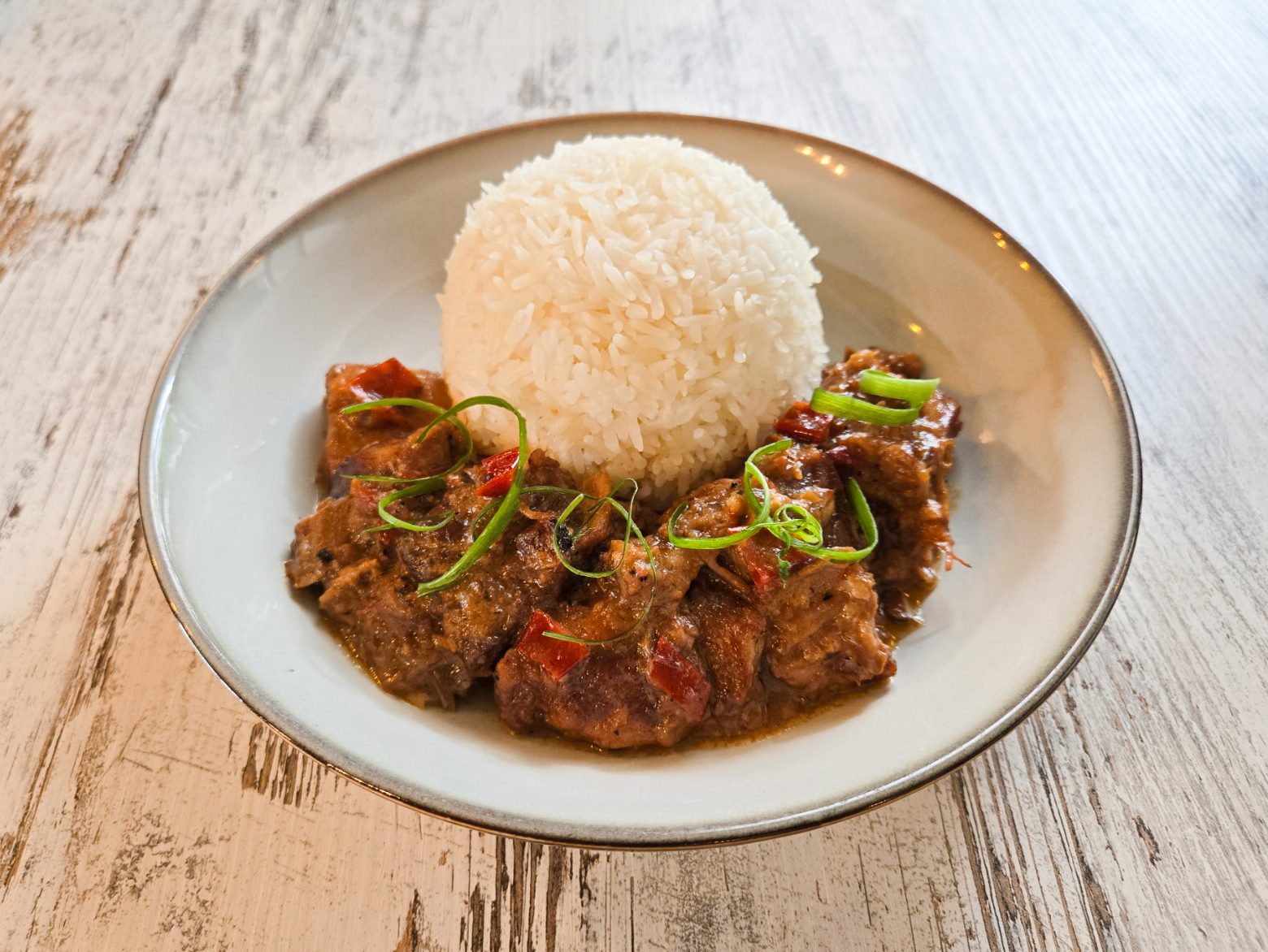 Filipino Bicol Express rice bowl — spicy pork and coconut milk stew with chili, shrimp paste, and steamed white rice.