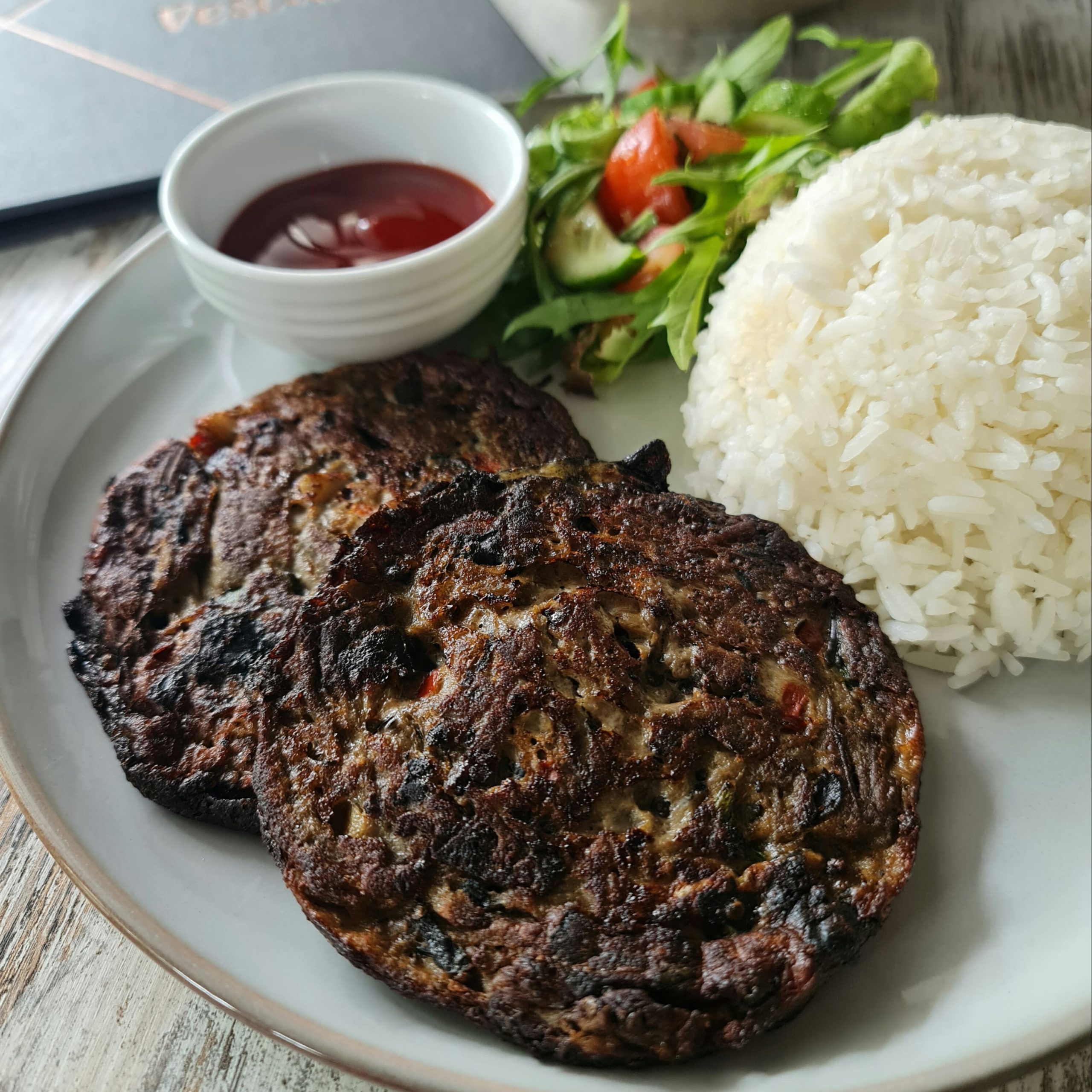 Filipino eggplant omelette with jasmine rice, mesclun salad, tomato, cucumber, and banana ketchup at Descanso Café in Newtown Sydney.